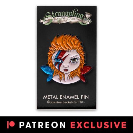 Tiny Bowie fairy pin is an enamel pin of a big eyed fairy with one blue eye, one brown eye, blue and red sparkly wings and red and blue lightening bolt on its face on logo backing card